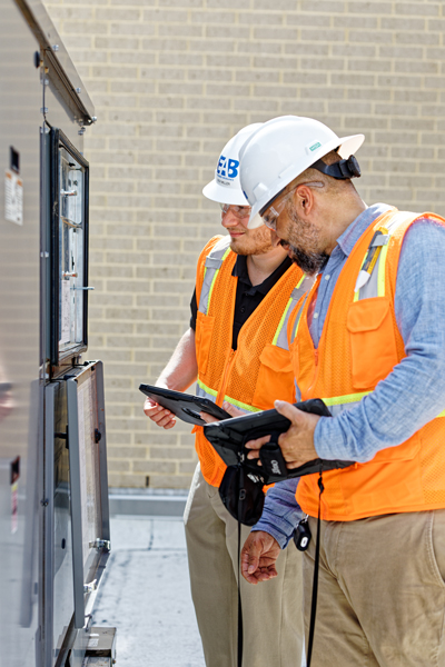 two commissioning engineers holding a tablet